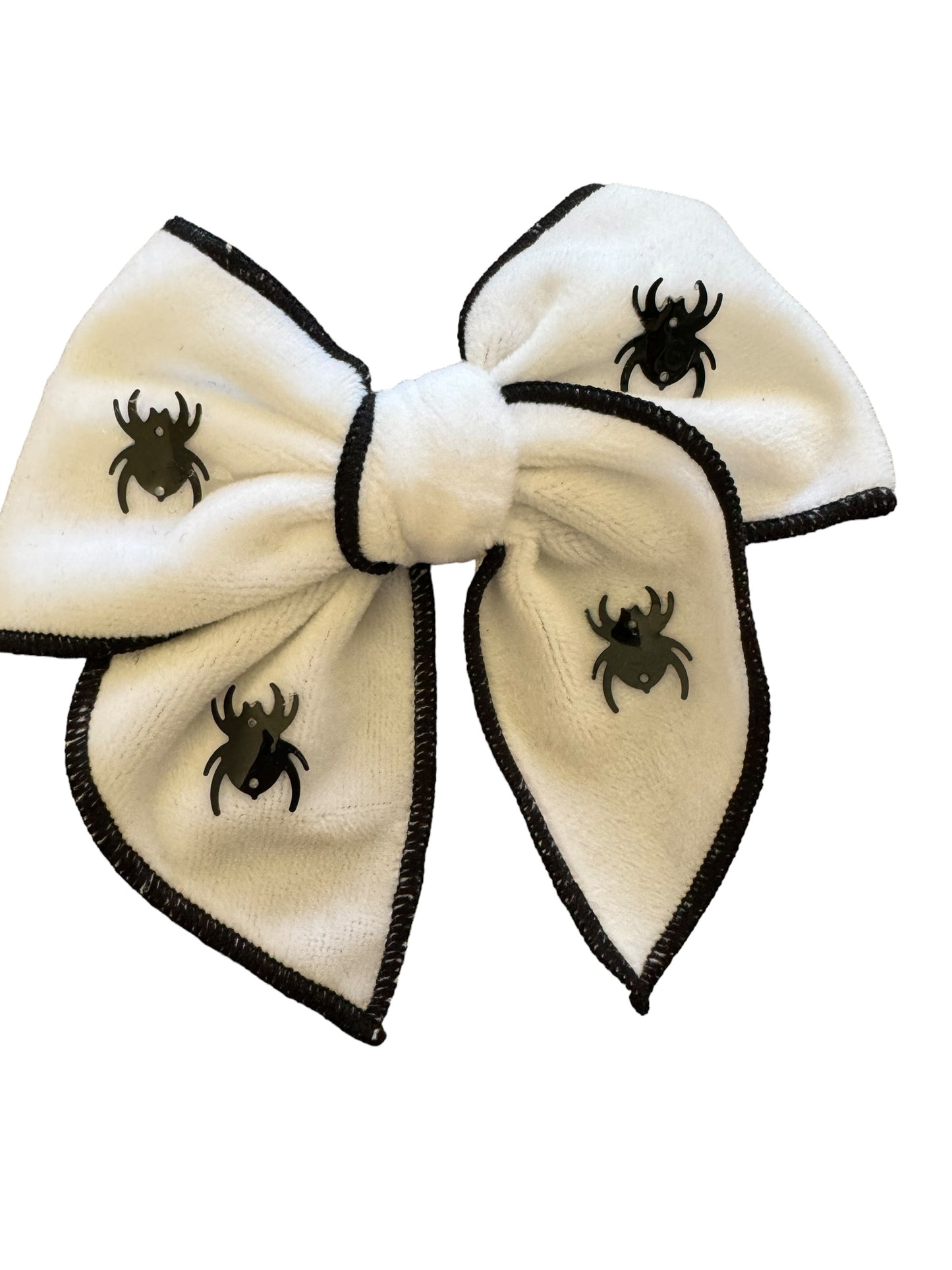 A white velvet hair bow with black spider decorations and black trim.