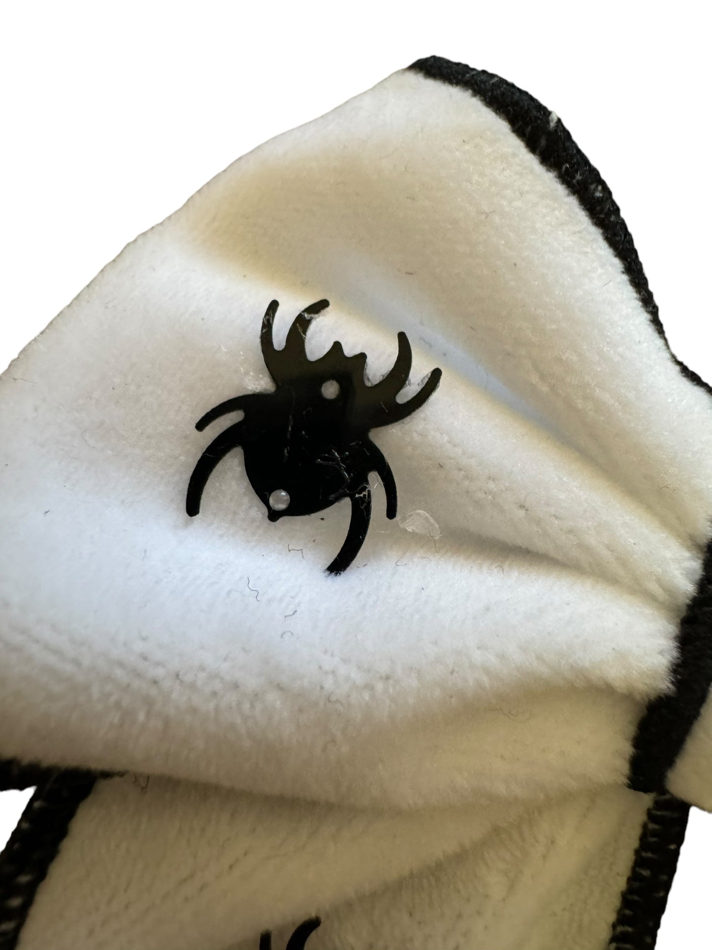 A white velvet hair bow with black spider decorations and black trim close up