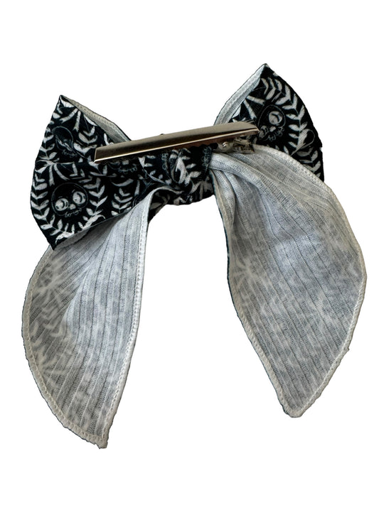 A set of black and white skeleton patterned hair bows on alligator clips
