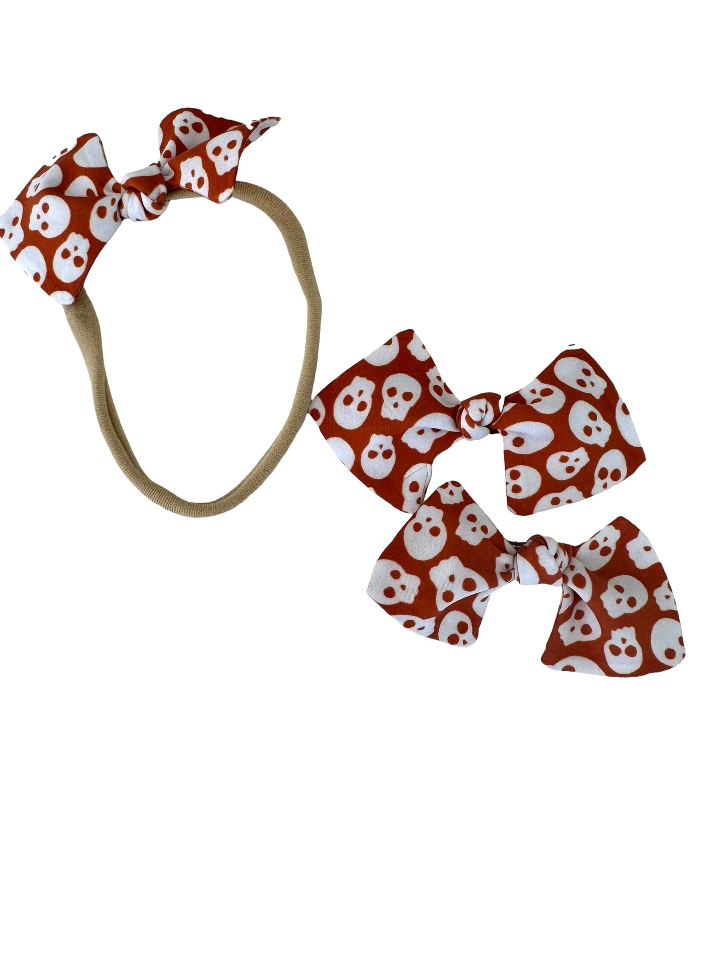 orange and white skulls on a nylon headband for babies and clips for pigtails
