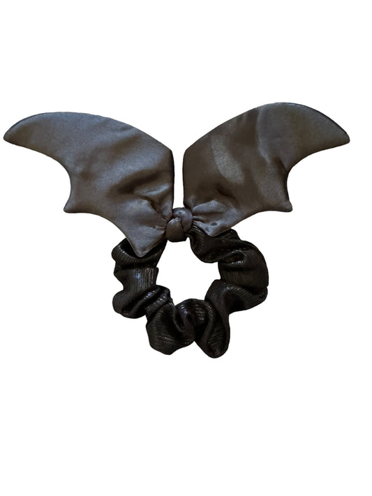 A black satin scrunchie with bat wings attached and a sparkly tie in the center.