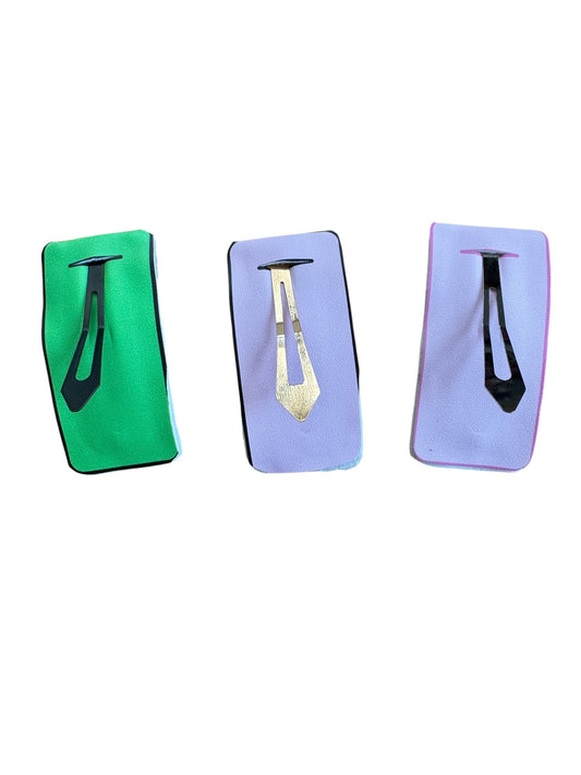 Three hair clip products in green, purple, and black packaging on a white background