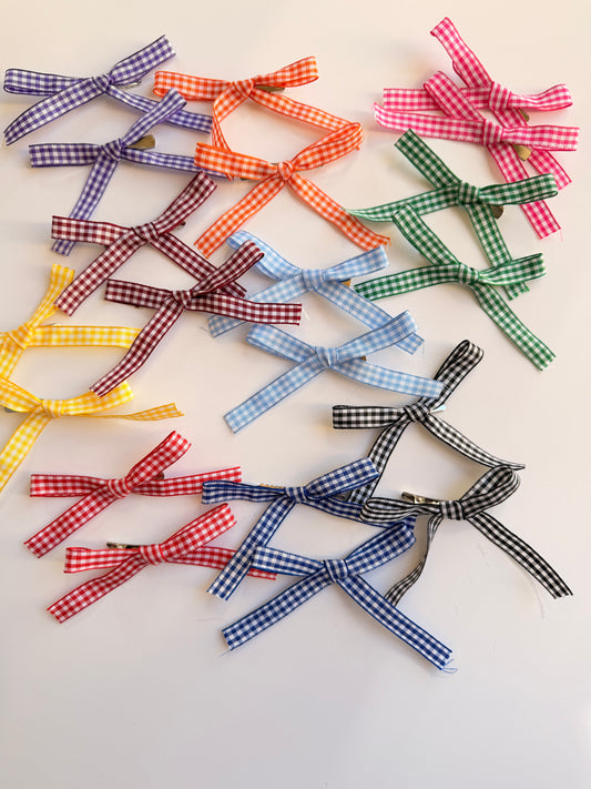 A collection of small ribbon bows in assorted gingham patterns and colors, including purple, orange, pink, green, red, yellow, light blue, dark blue, and black, arranged on a plain white background.