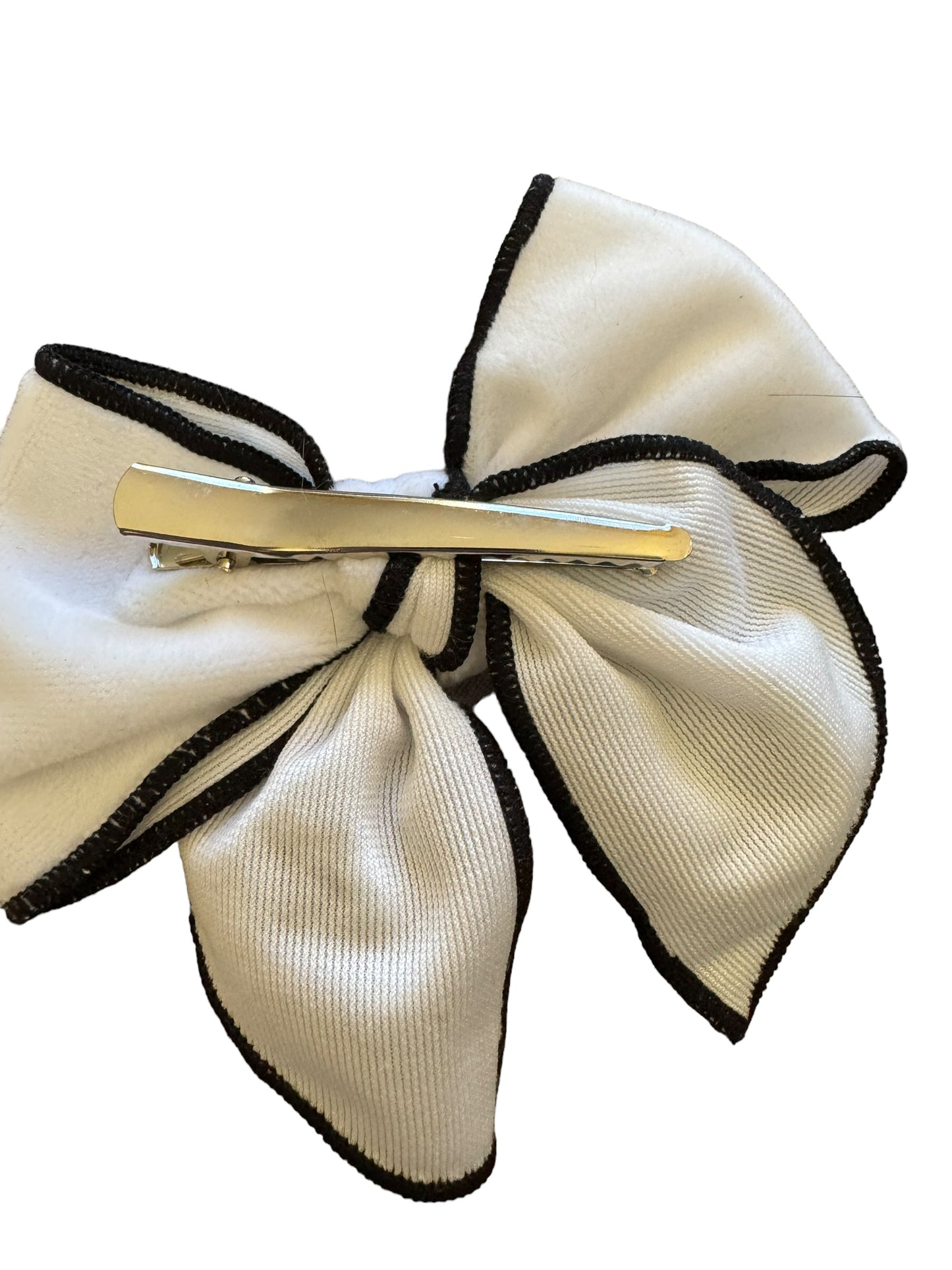 A white velvet hair bow with alligator clip and black trim