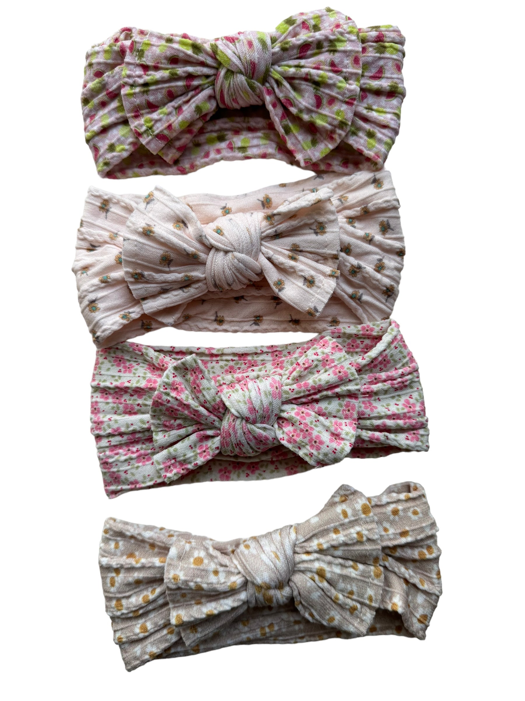 A few patterned nylon headwraps for babies with large bow on white background