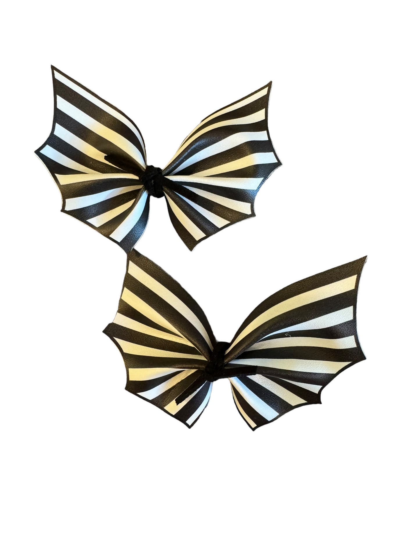 Two black and white striped bat-shaped faux leather hair bows with alligator clips attached.