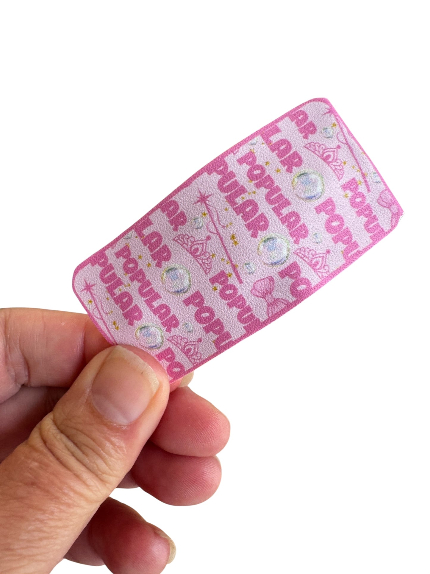 Pink snap clip with text held by a hand on a white background