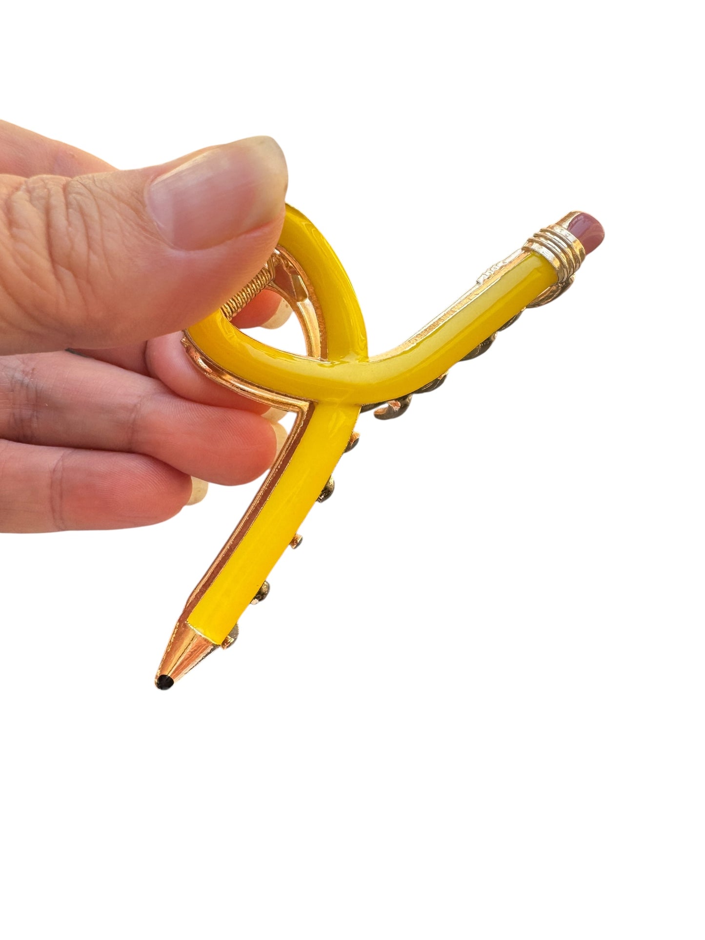 Yellow pencil claw clip with a unique design held by a hand on a white background