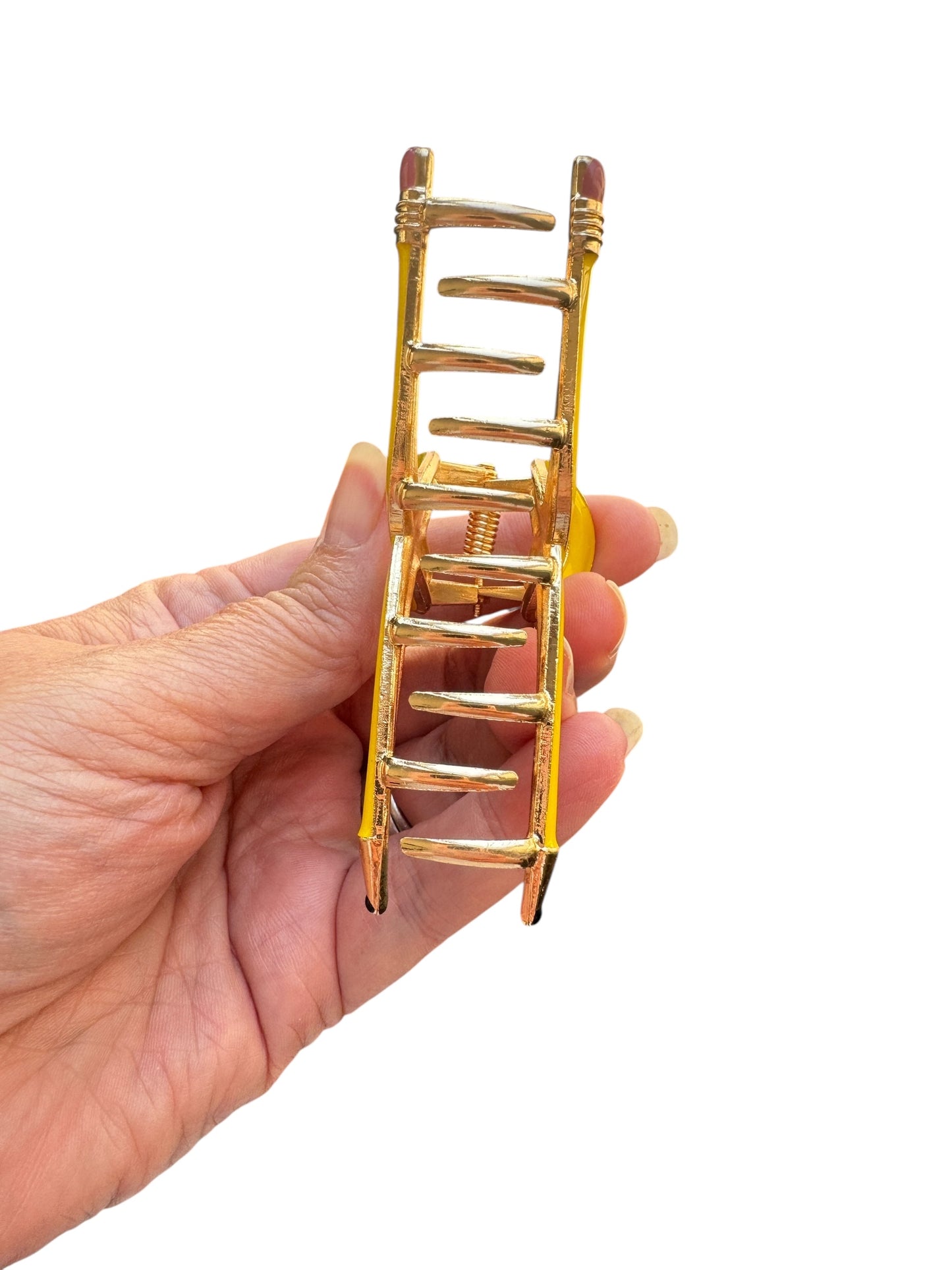 Yellow pencil claw clip with a unique design held by a hand on a white background
