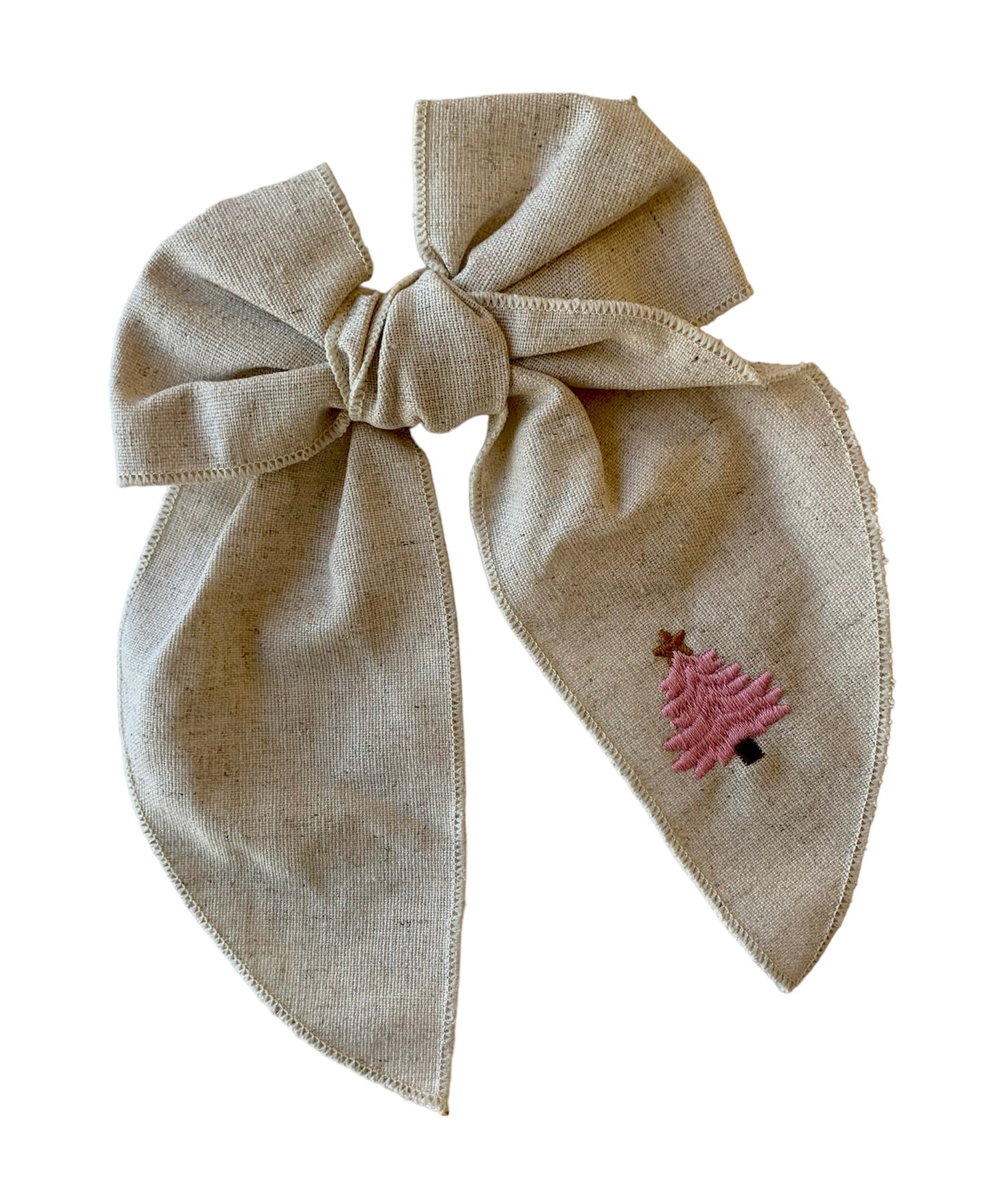 A beige linen hair bow with a Christmas tree embroidery on it, attached to an alligator clip.