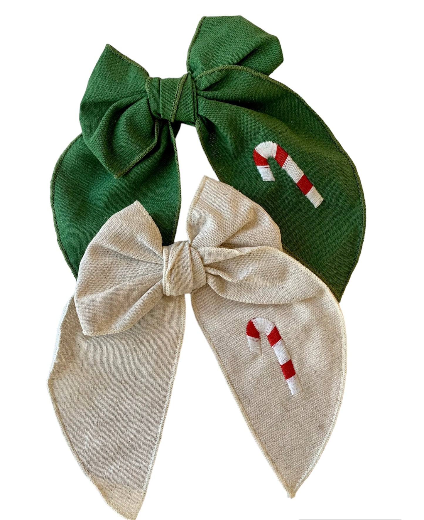 A beige and a green linen hair bow with a Christmas candy cane embroidery on it, attached to an alligator clip.