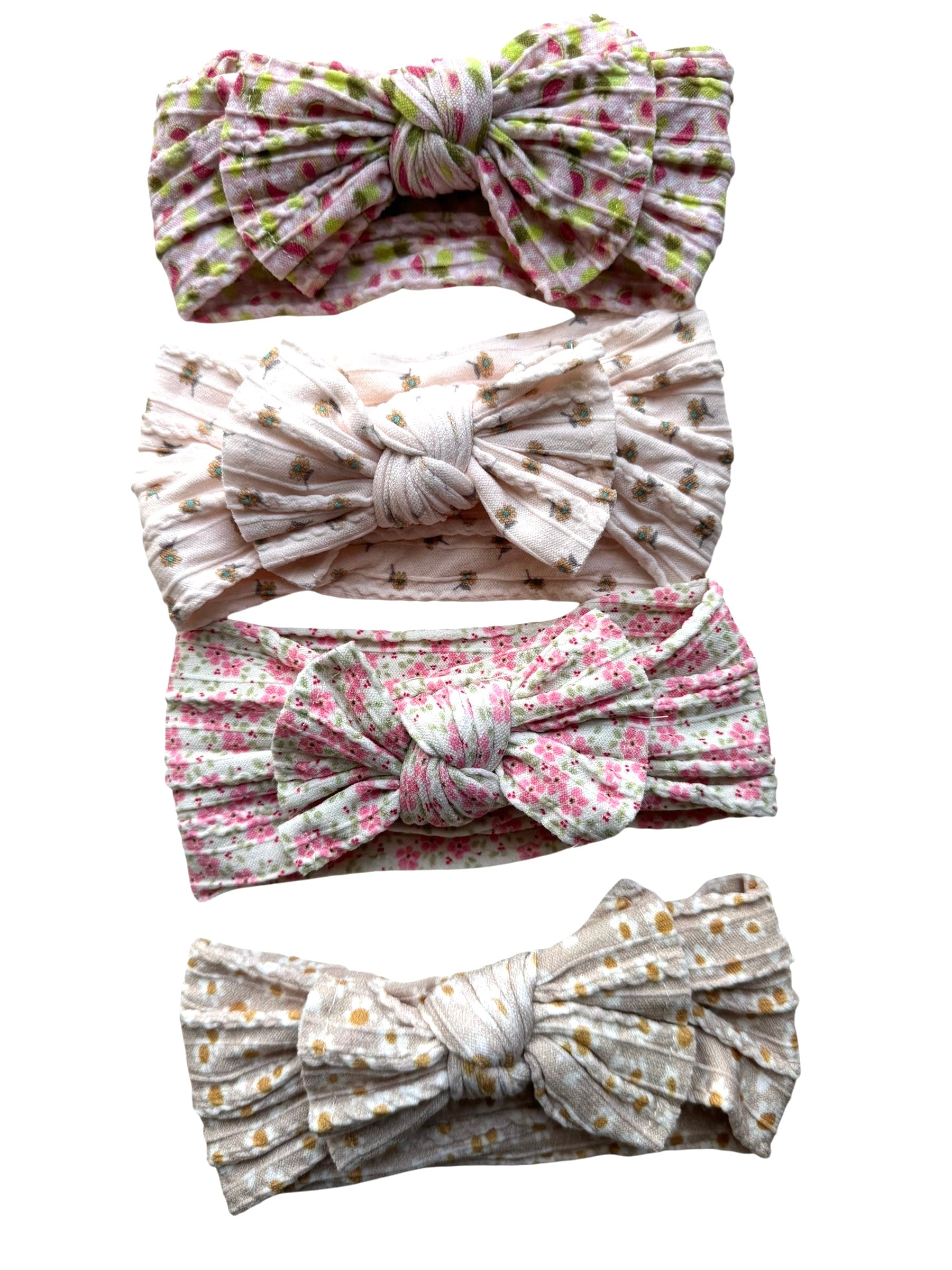 A few patterned nylon headwraps for babies with large bow on a white background