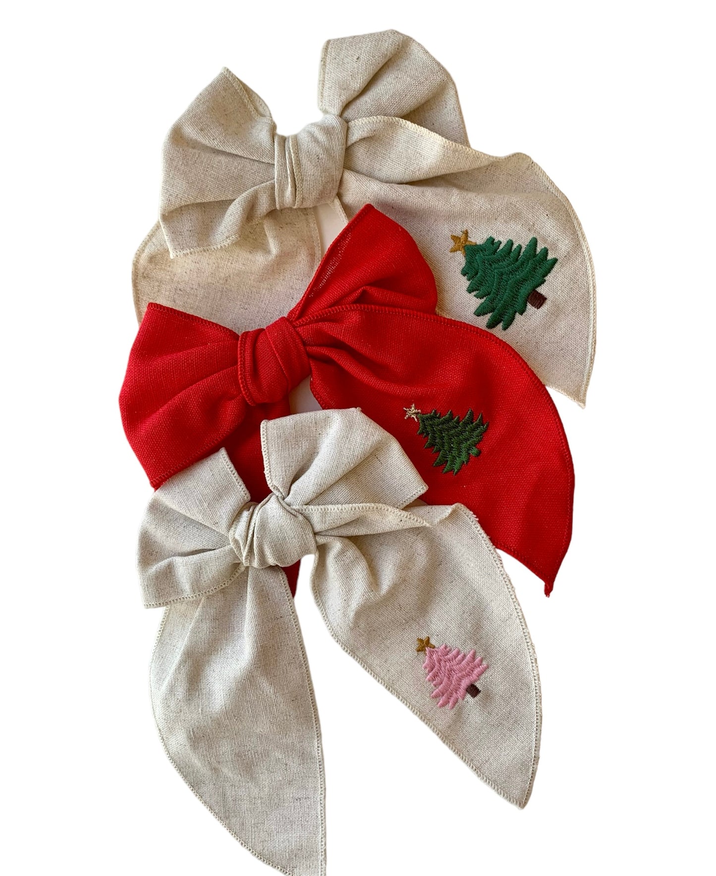 A Red and beige linen hair bow with a Christmas tree embroidery on it, attached to an alligator clip.
