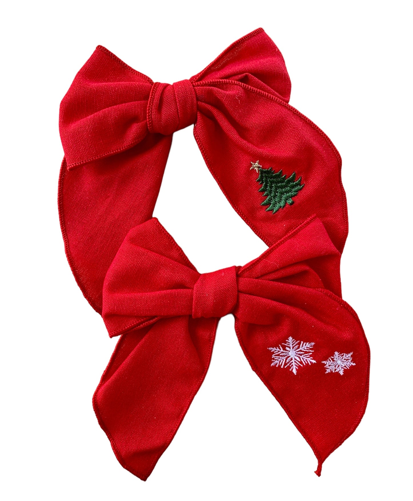 A Red linen hair bow with a Christmas tree and a snowflake embroidery on it, attached to an alligator clip.