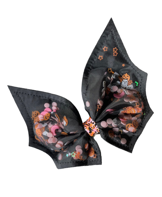 A black hair clip with a bow and bat design, featuring Halloween sprinkles inside the bow.