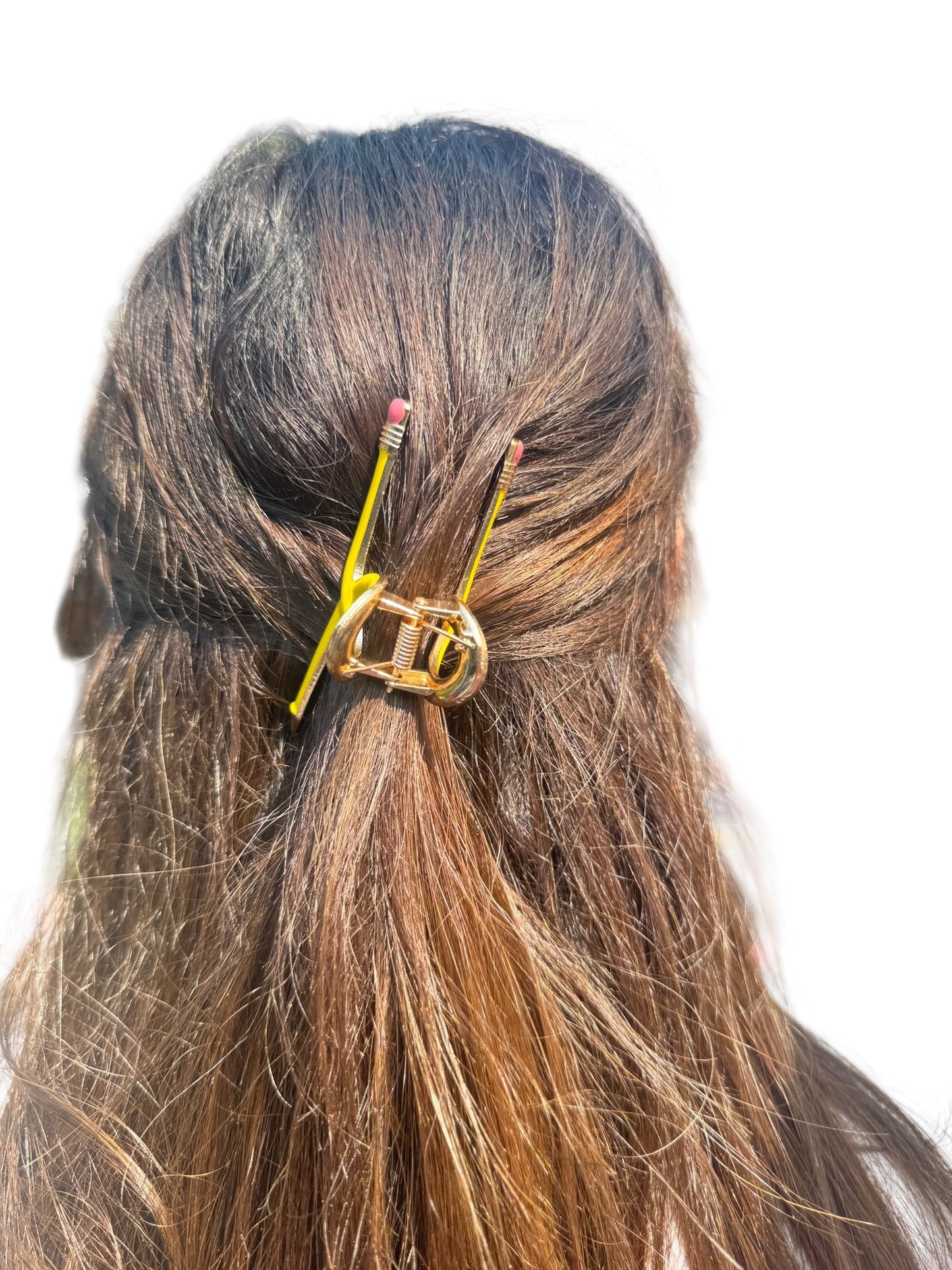 Hair clip shaped like a yellow pencil with pink eraser on brown hair against a white background