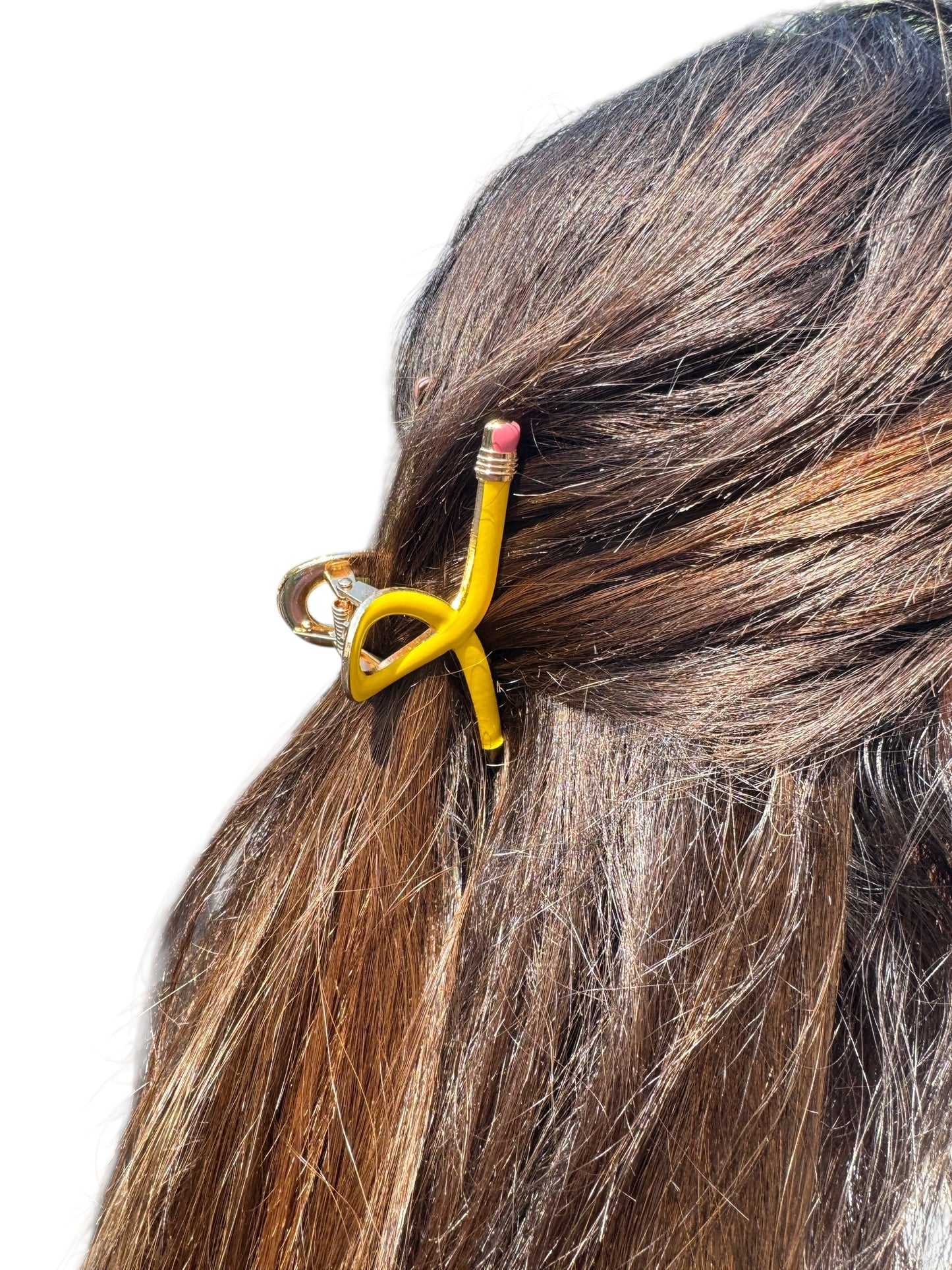 Hair clip shaped like a yellow pencil with pink eraser on brown hair against a white background