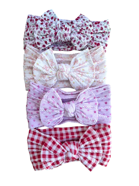 A set of patterned nylon headwraps for babies with large bows, displayed in a variety of colors and patterns.