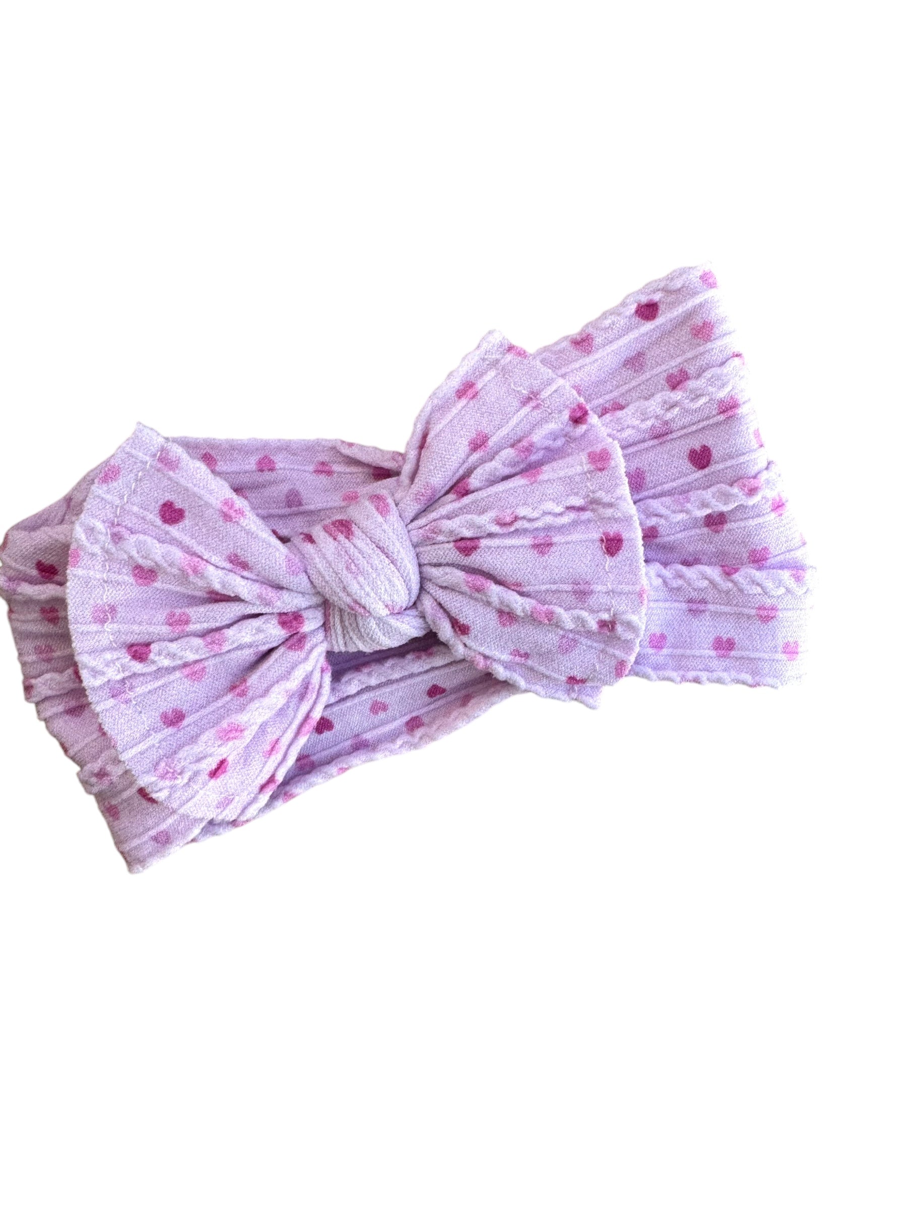 A pink heart  patterned nylon headband for babies with large bow