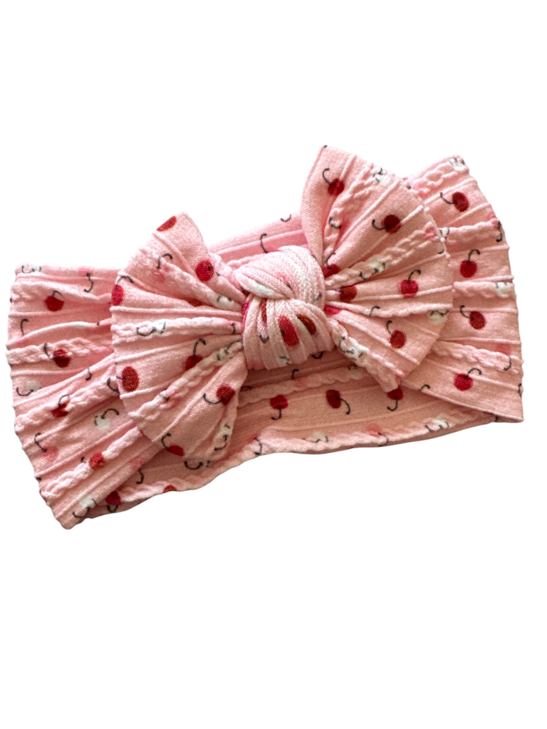 A red cherry patterned pink infant headband for babies with large bow