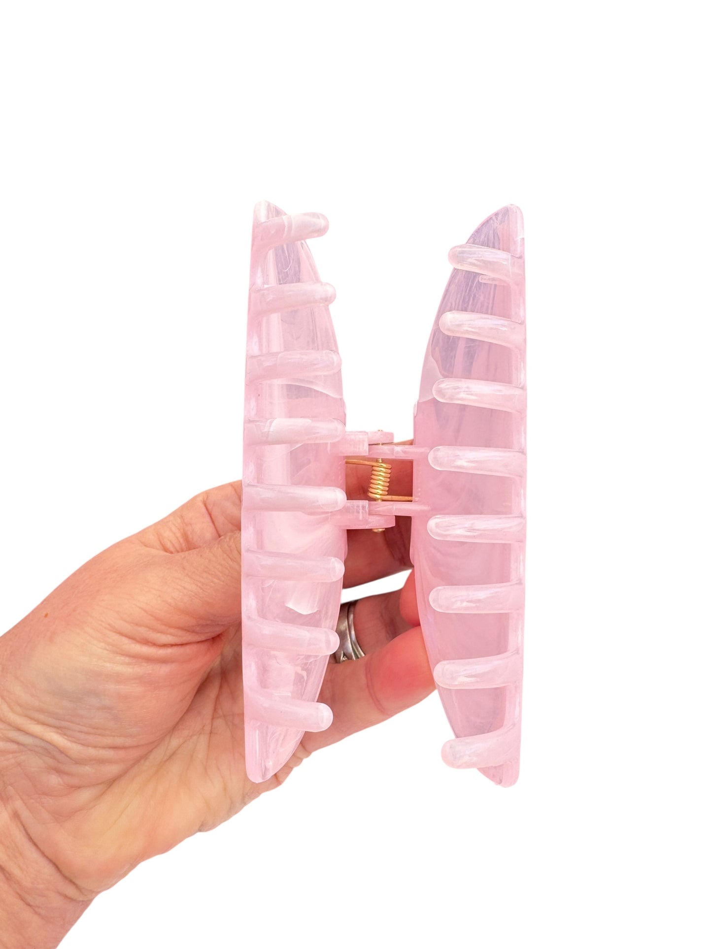 Pink hair tie with a clear plastic casing held in a hand against a white background