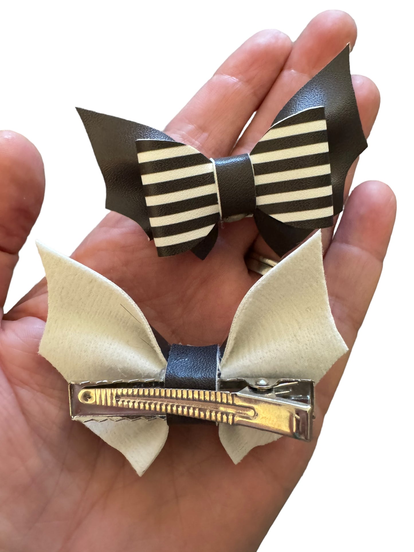 Two pigtail hair bows with black and white stripes and bat-shaped cutouts, attached to alligator clips.