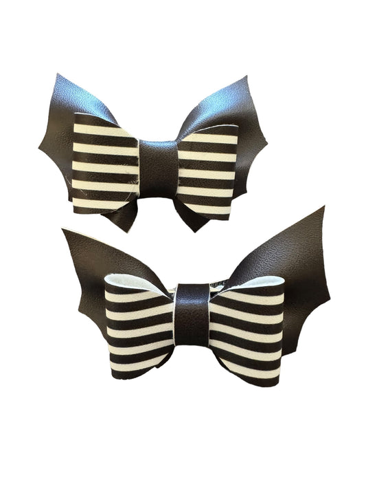 Two pigtail hair bows with black and white stripes and bat-shaped cutouts, attached to alligator clips.