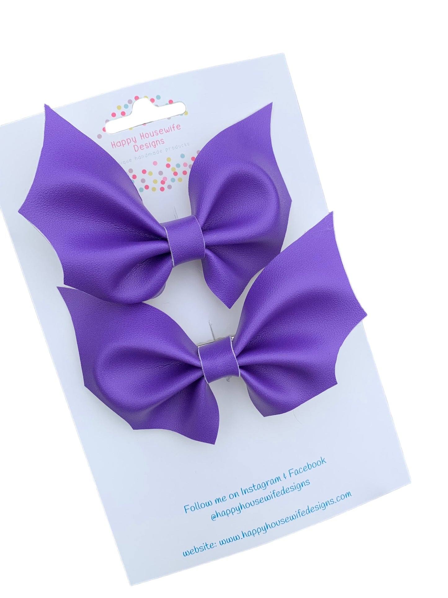 A set of faux leather hair bows in various colors with an alligator clip attached, displayed on a card.
