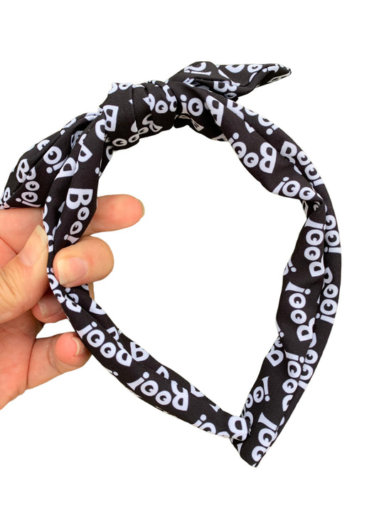 A black headband with the word 'BOO' printed in white pattern, designed for Halloween.