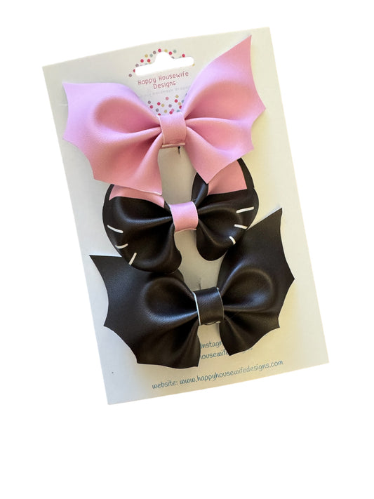 A set of faux leather hair bows in various colors with an alligator clip attached, displayed on a card.