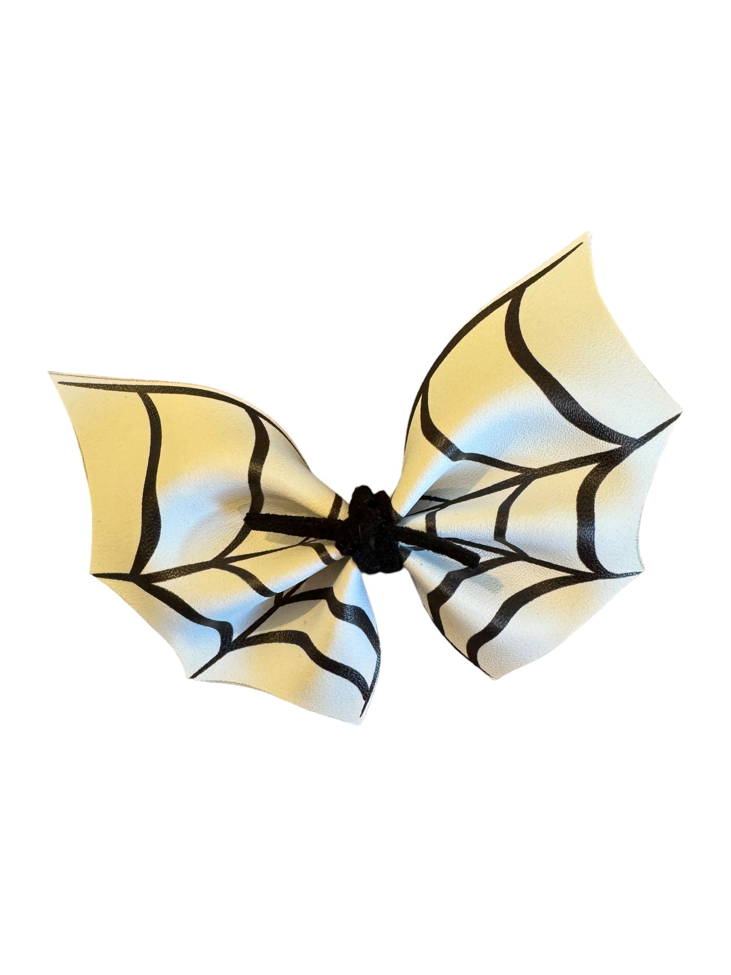 A faux leather hair bow with a spider web pattern attached to an alligator clip, displayed on a white background
