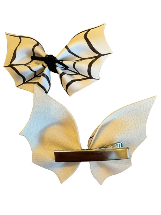 A faux leather hair bow with a spider web pattern attached to an alligator clip, displayed on a white background showing one on an alligator clip