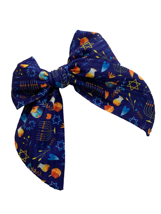 A blue hair bowwith patterned designs including stars and menorahs.