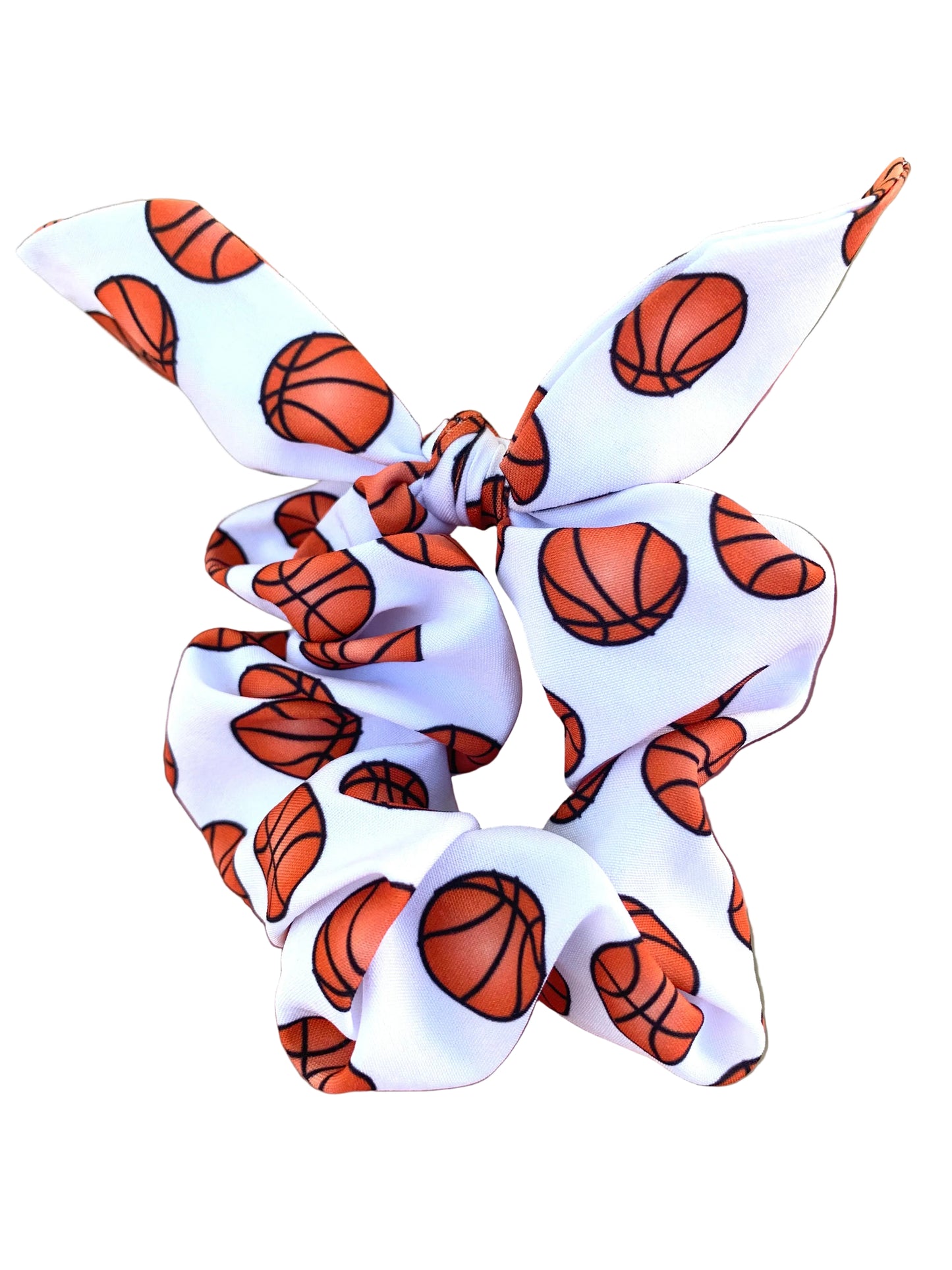 A white and brown sports scrunchie with a pattern that resembles a basketball and its stitching.