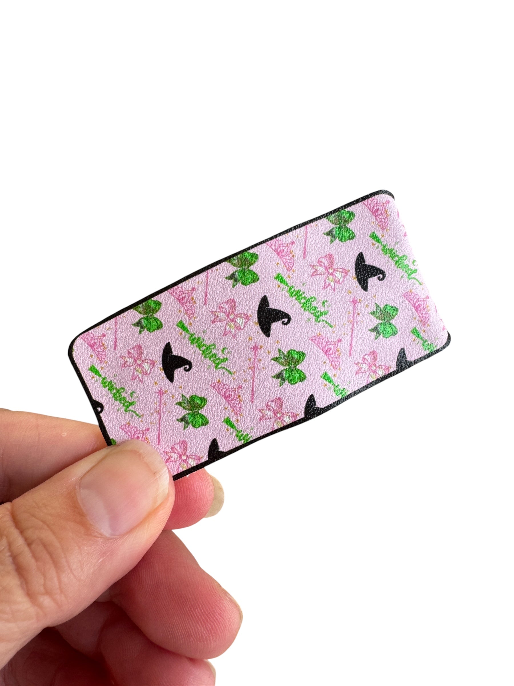 Small rectangular snap clip with fairy and unicorn design held by a hand on a white background