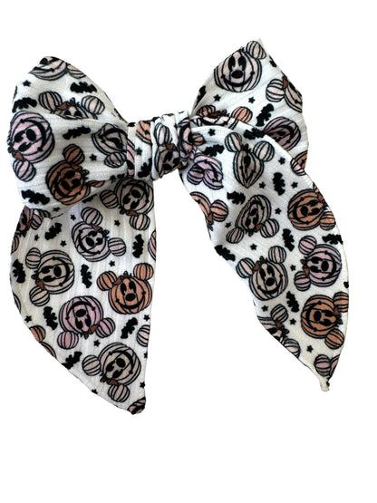 A set of hair bows with a pumpkin and mouse pattern displayed on alligator clips