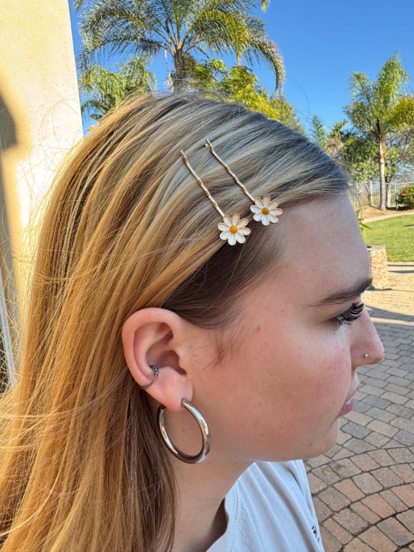 Woman with floral hairpins and hoop earrings outdoors