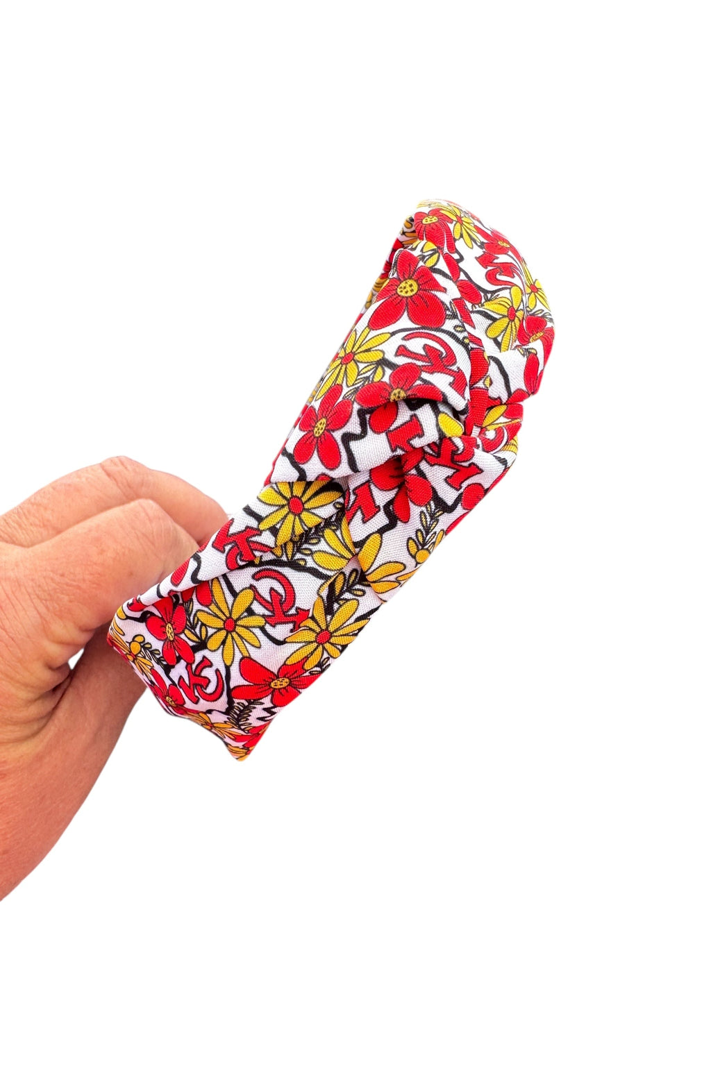 Hand holding a colorful floral-patterned headband against a white background