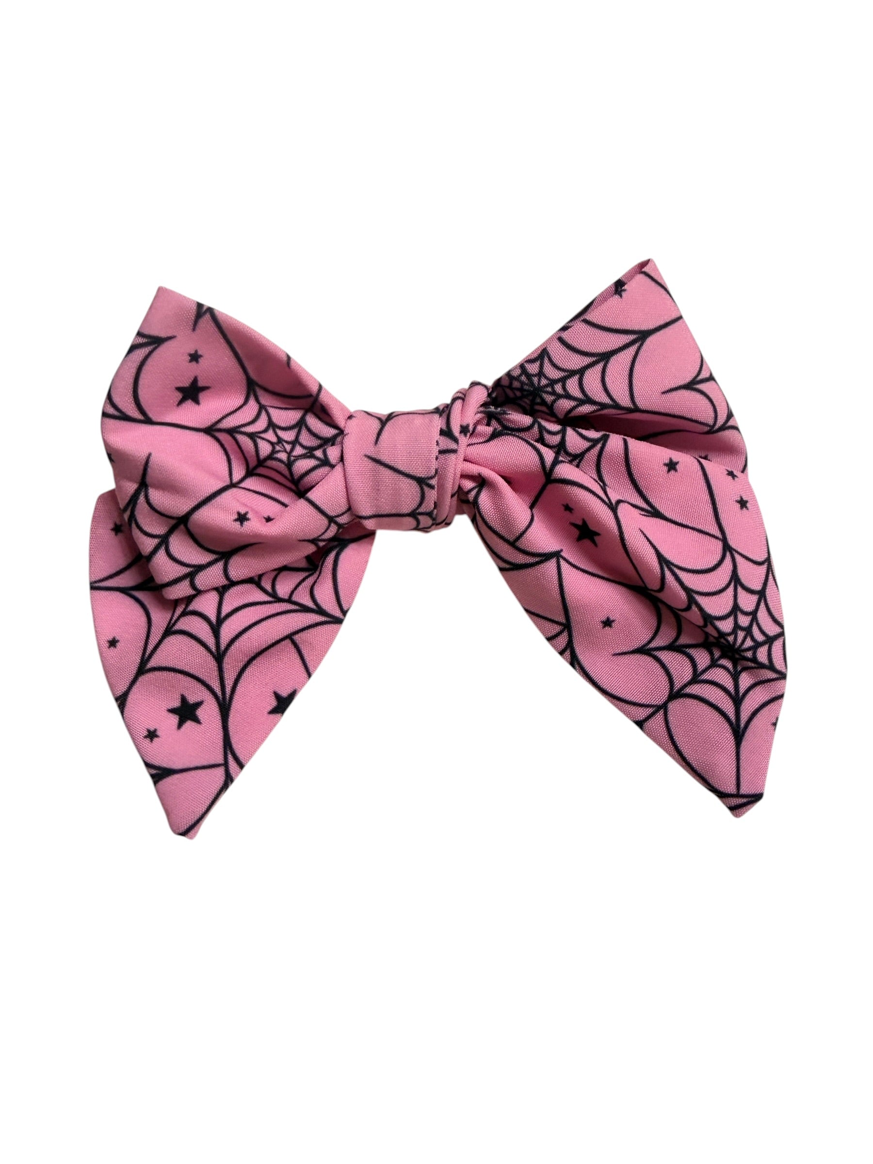 A pink hair bow featuring a black spiderweb and star pattern, presented on a solid white background.