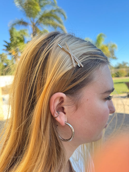 Person with blonde hair and earrings against a blue sky