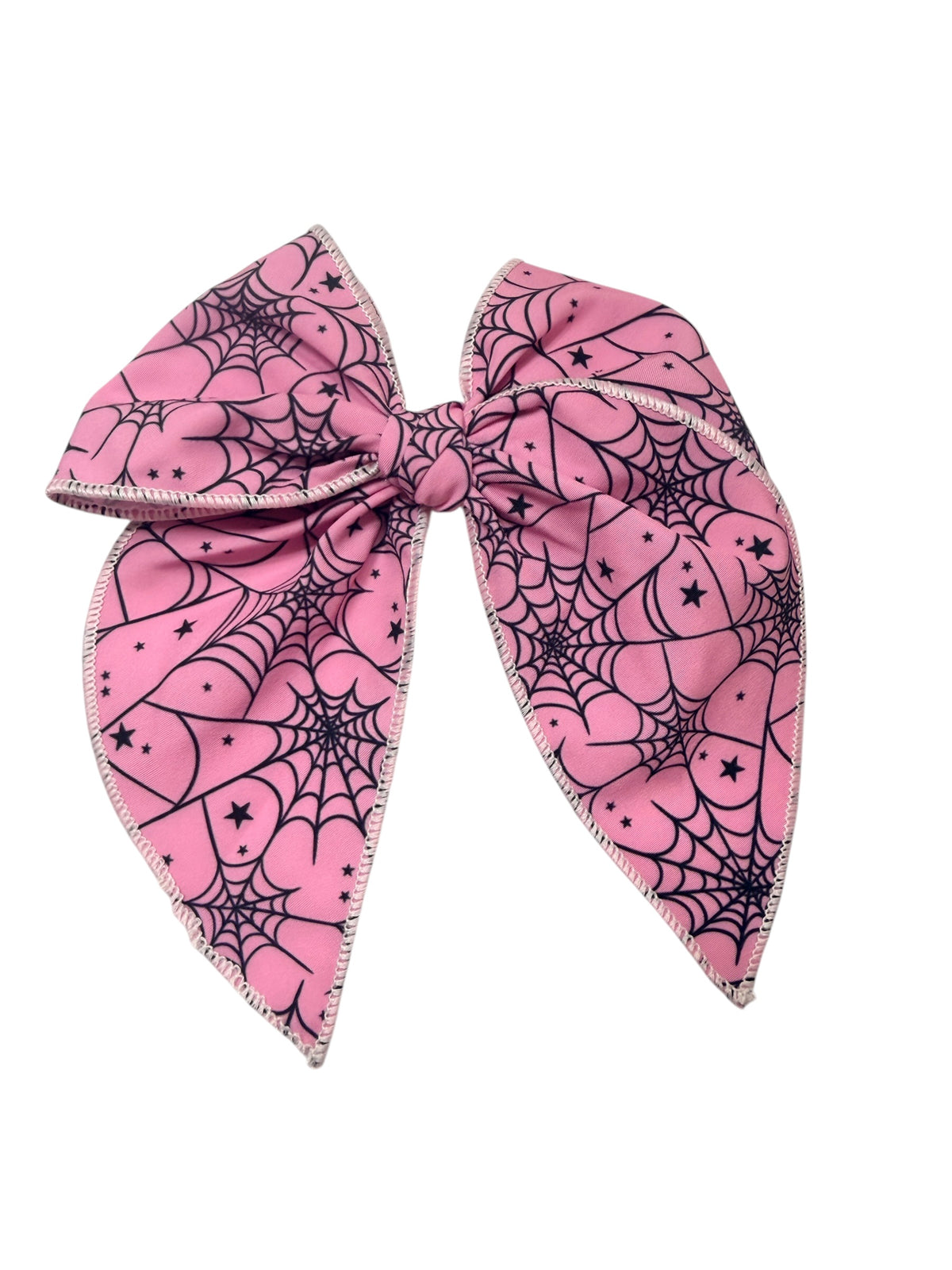 A pink hair bow featuring a black spiderweb and pumpkin pattern with small black stars, finished with a silver glitter trim, shown on a plain white background.