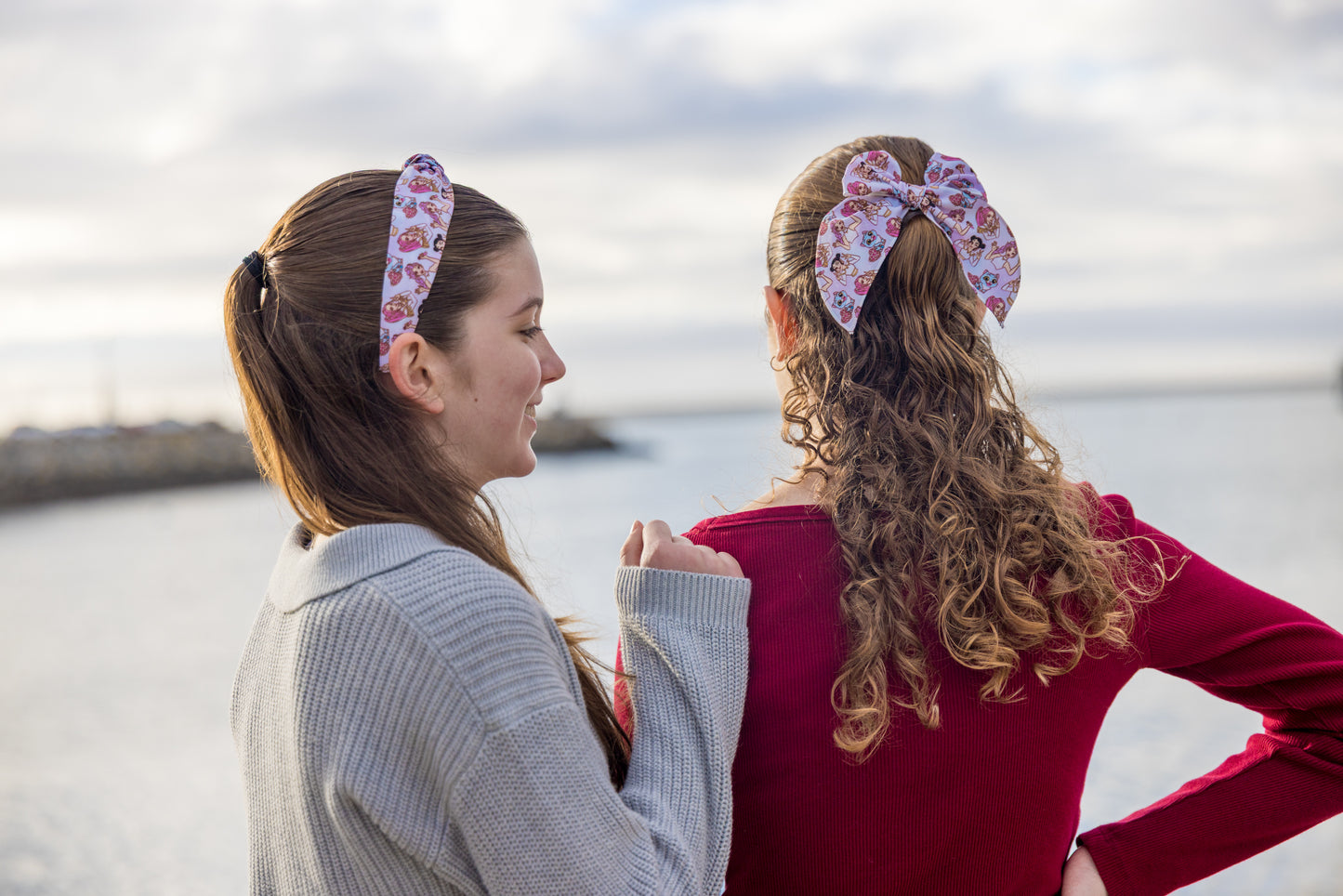 Two girls wearing floral headbands by a body of water.
