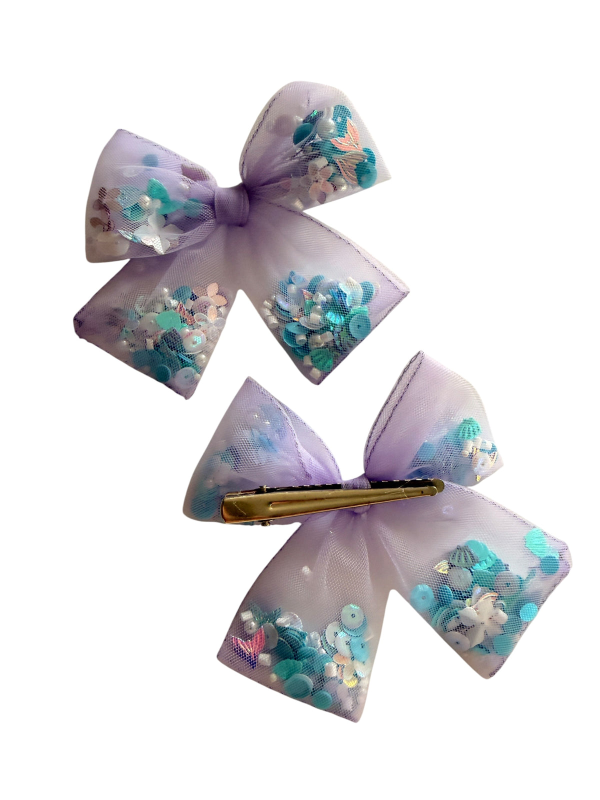Two lavender tulle hair bows filled with blue, teal, and iridescent sequins, shown on a plain white background. One bow features a gold metal clip.