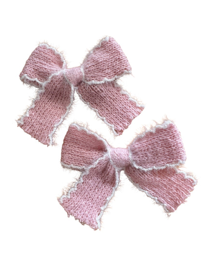 Two pink knitted bows on a white background