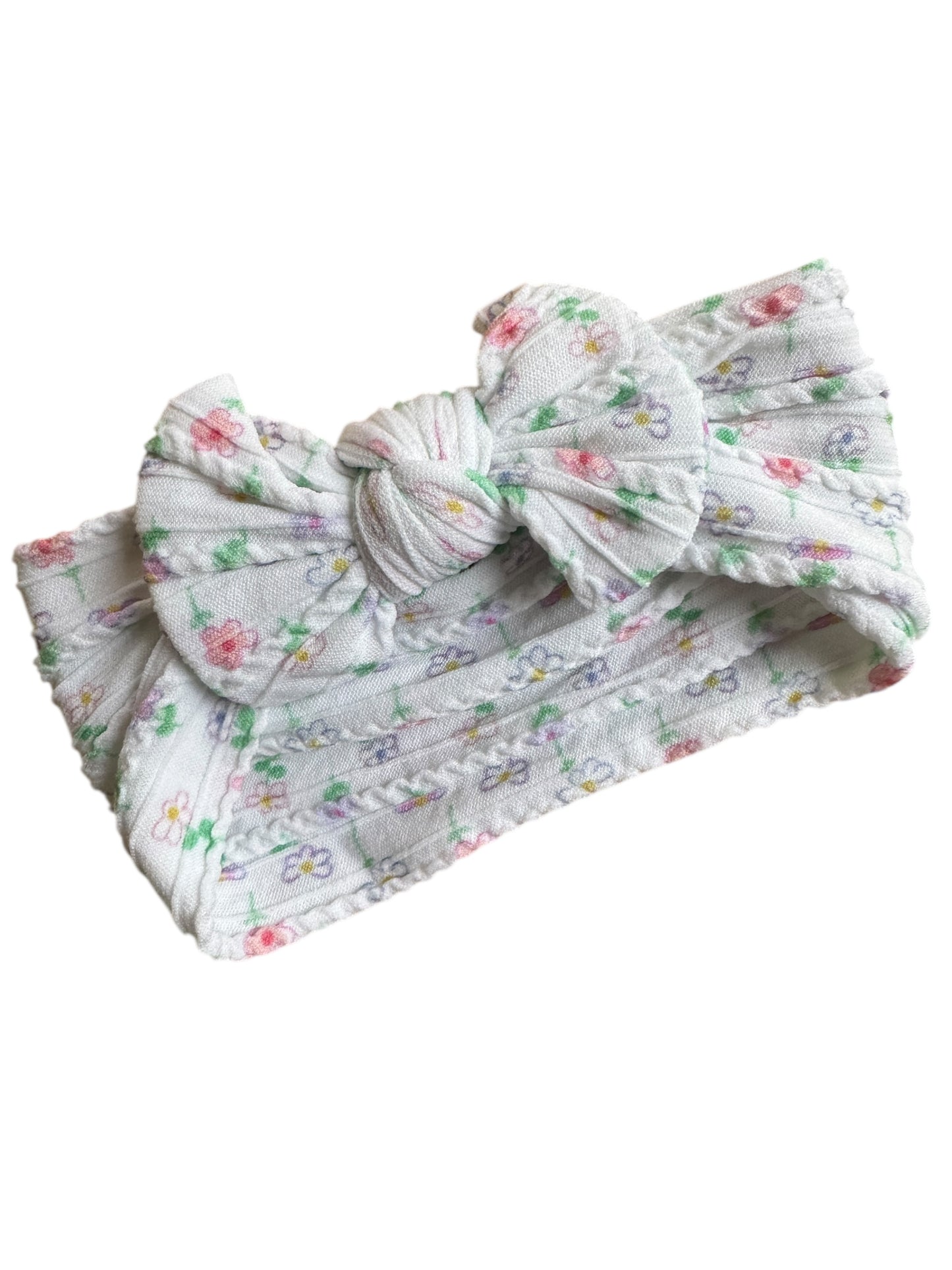 A floral patterned white infant headband for babies with large bow