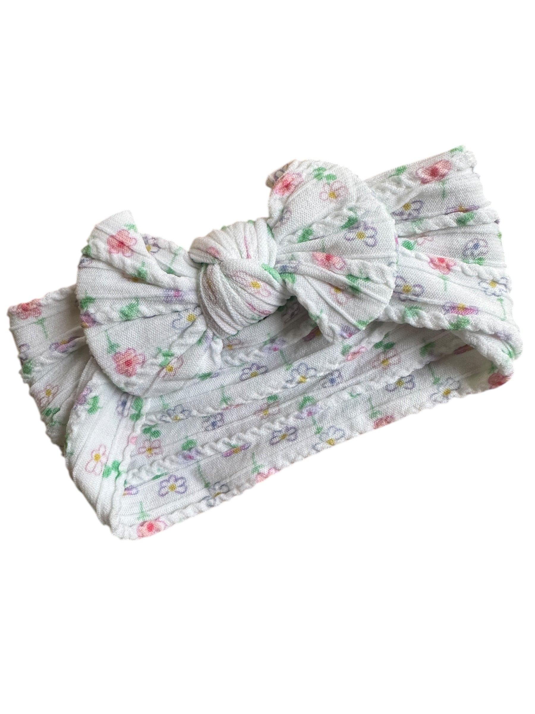 A floral patterned white infant headband for babies with large bow