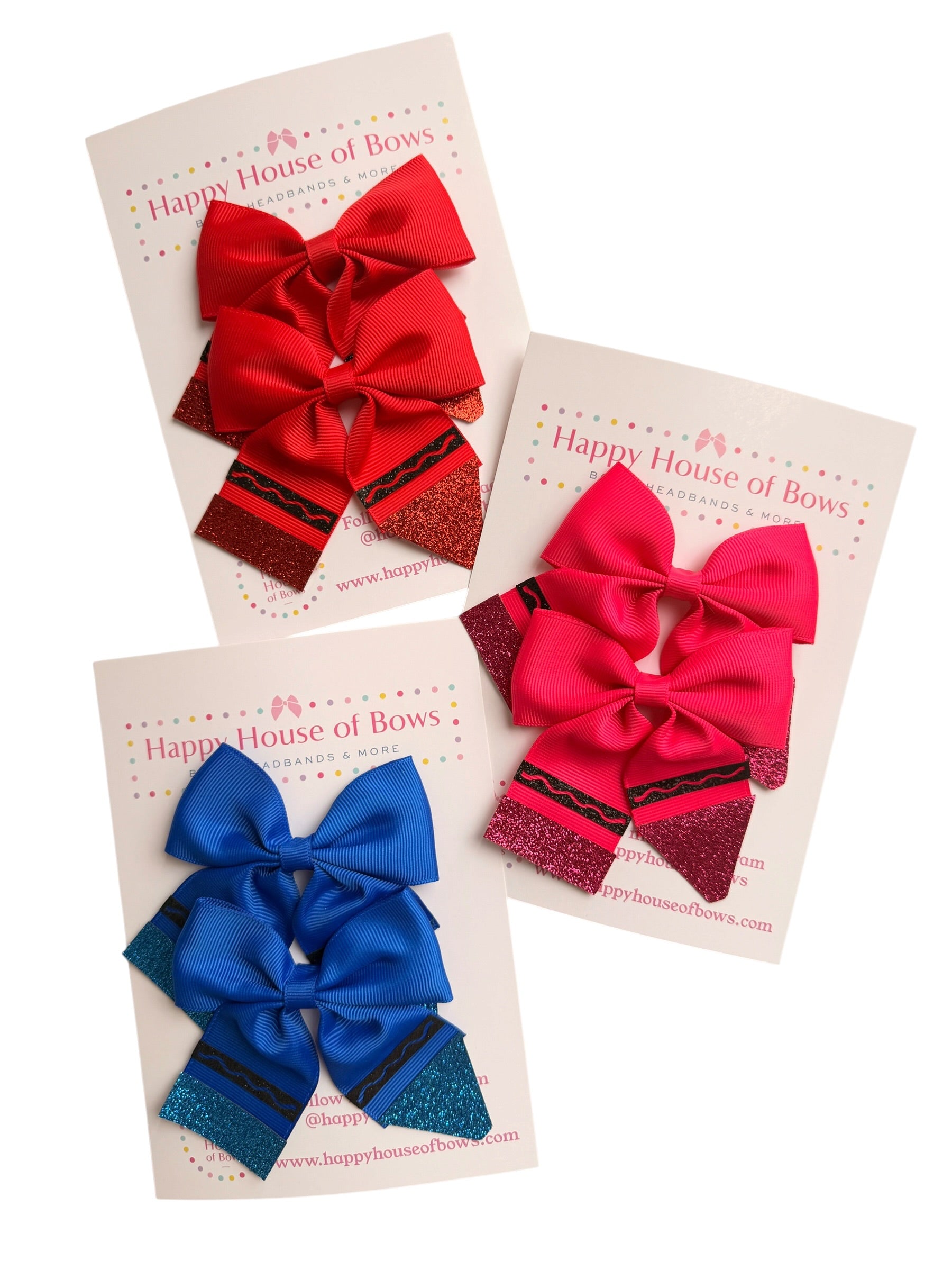 Three cheerleader hair bows displayed on branded backing cards: one red, one bright pink, and one royal blue, each with glittery striped accents.