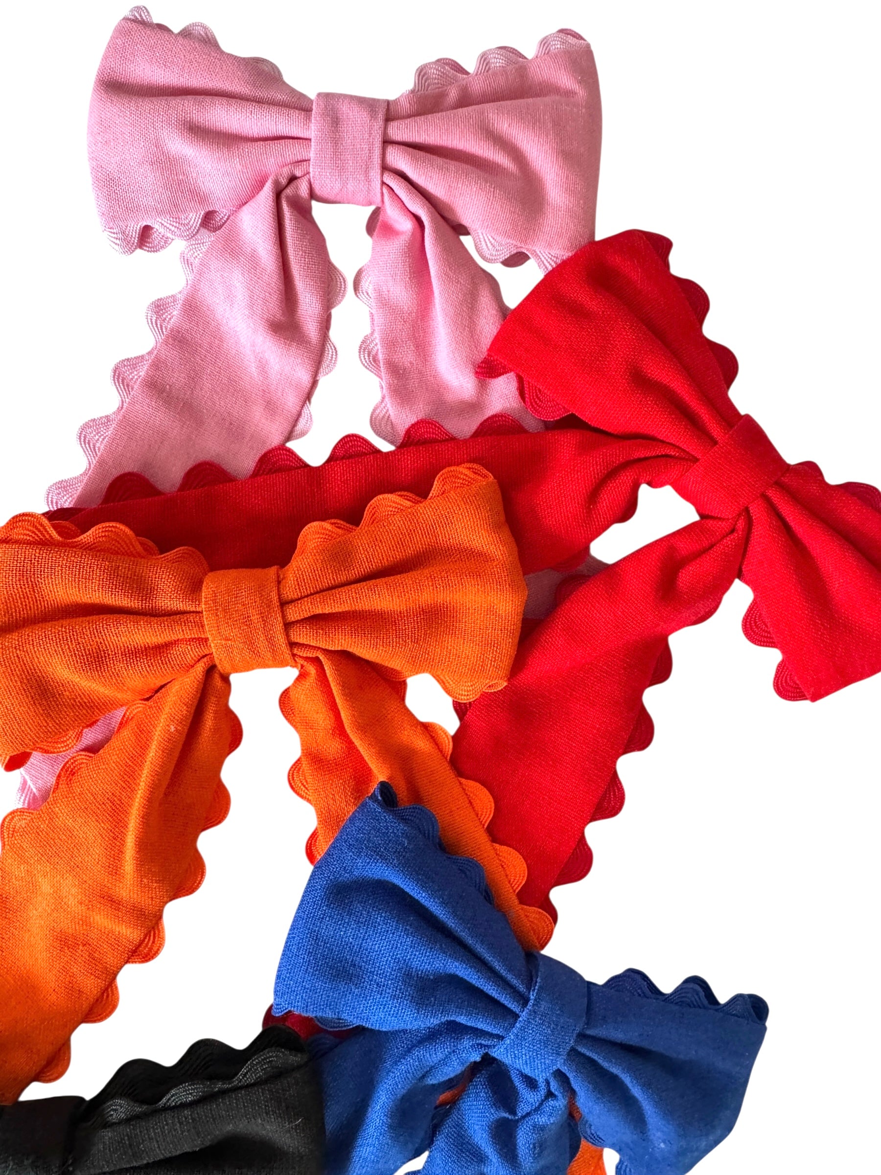Three colorful hair bows in pink, orange, and blue on a white background