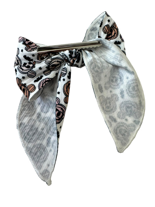 A set of hair bows with a pumpkin and mouse pattern displayed on alligator clips
