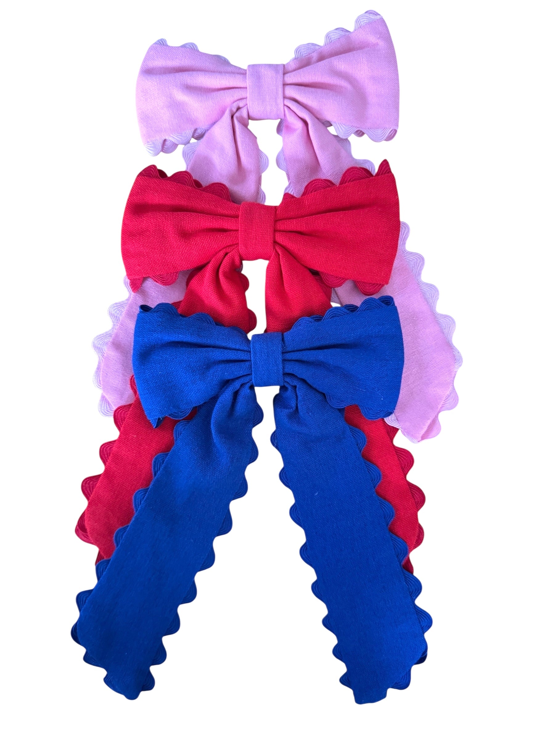 Three colorful hair bows in pink, red, and blue on a white background